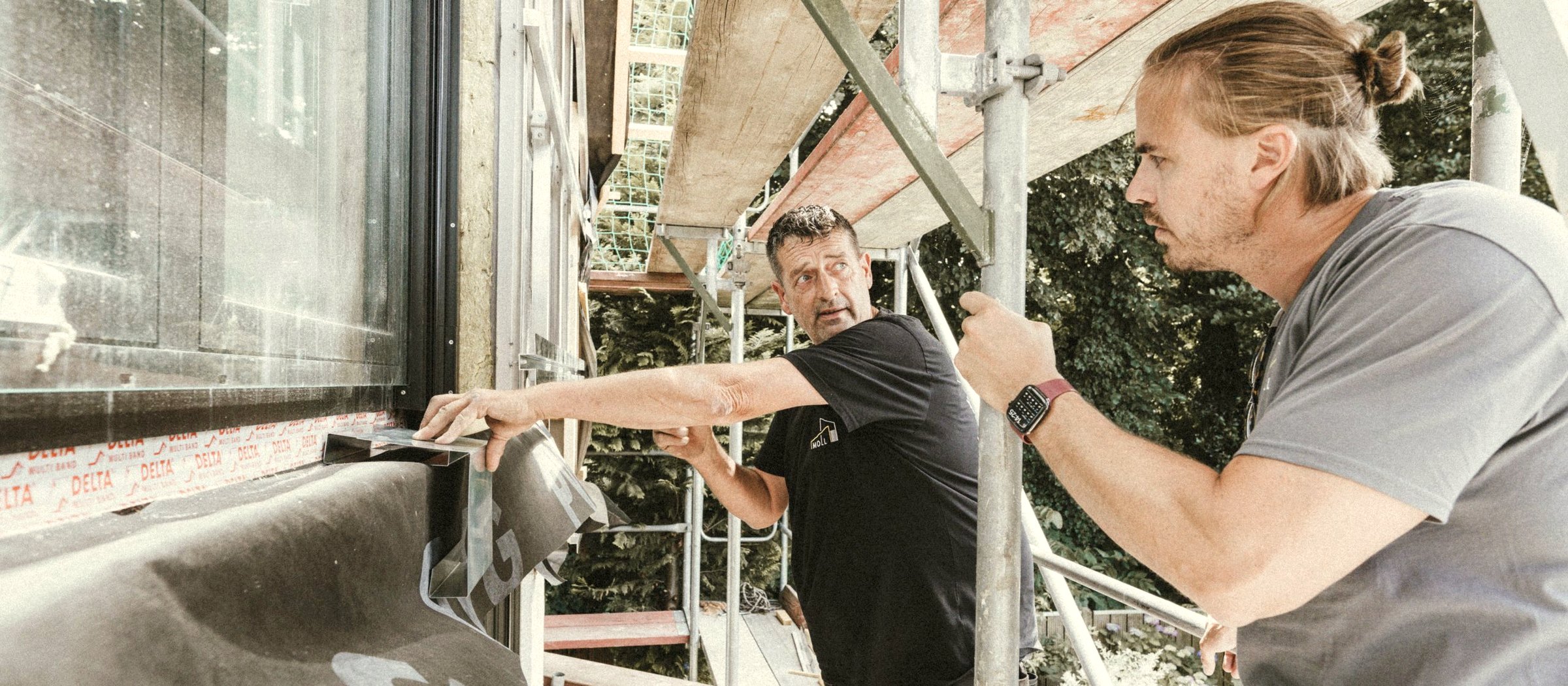 Zwei Dachdecker arbeiten Seite an Seite auf einem Steildach