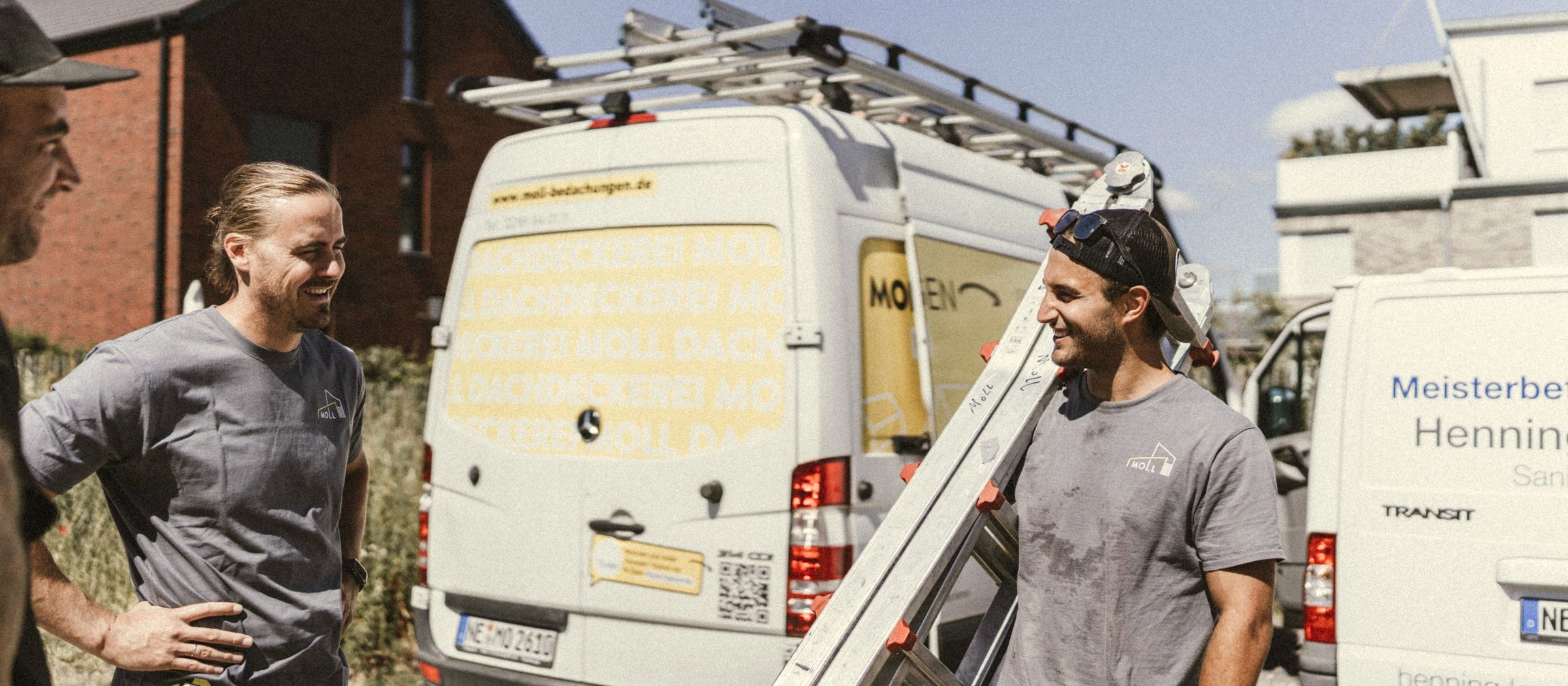Das Moll-Service-Team an einem Einsatzort — drei Dachdecker in Moll-Workshirts vor dem branded Servicefahrzeug