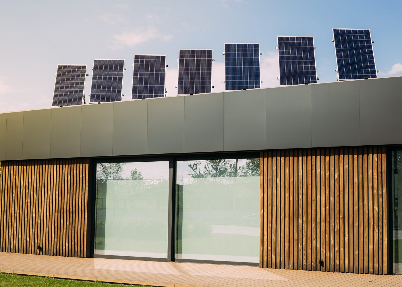 Modernes Gebäude mit Photovoltaik-Reihe auf dem Dach und Holzfassade — Kostenfaktoren einer Solaranlage
