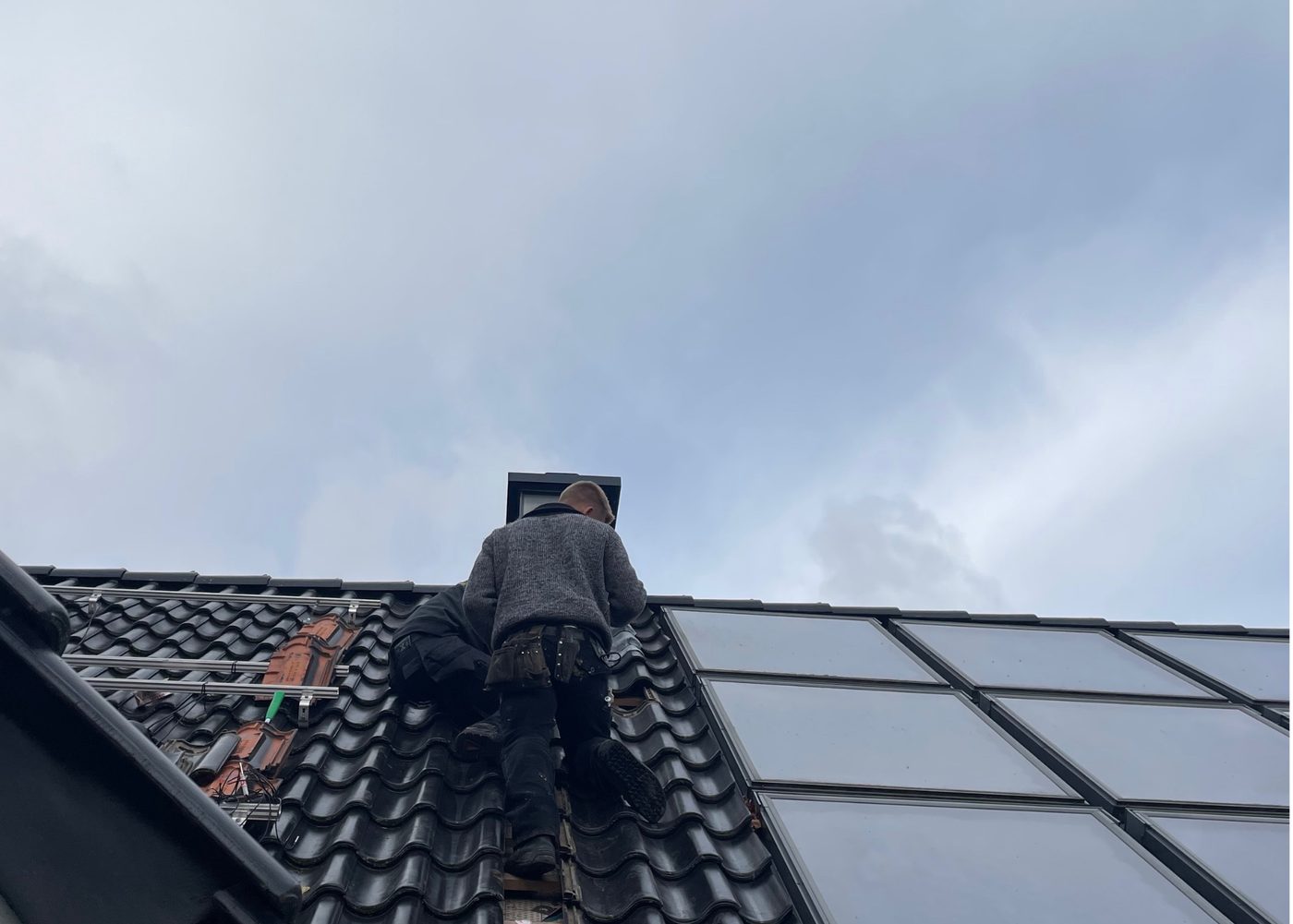 Monteur installiert Photovoltaik-Module auf einem Ziegeldach — Planung und Montage aus einer Hand